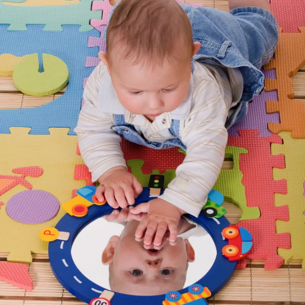 An image of baby playing with a mirror