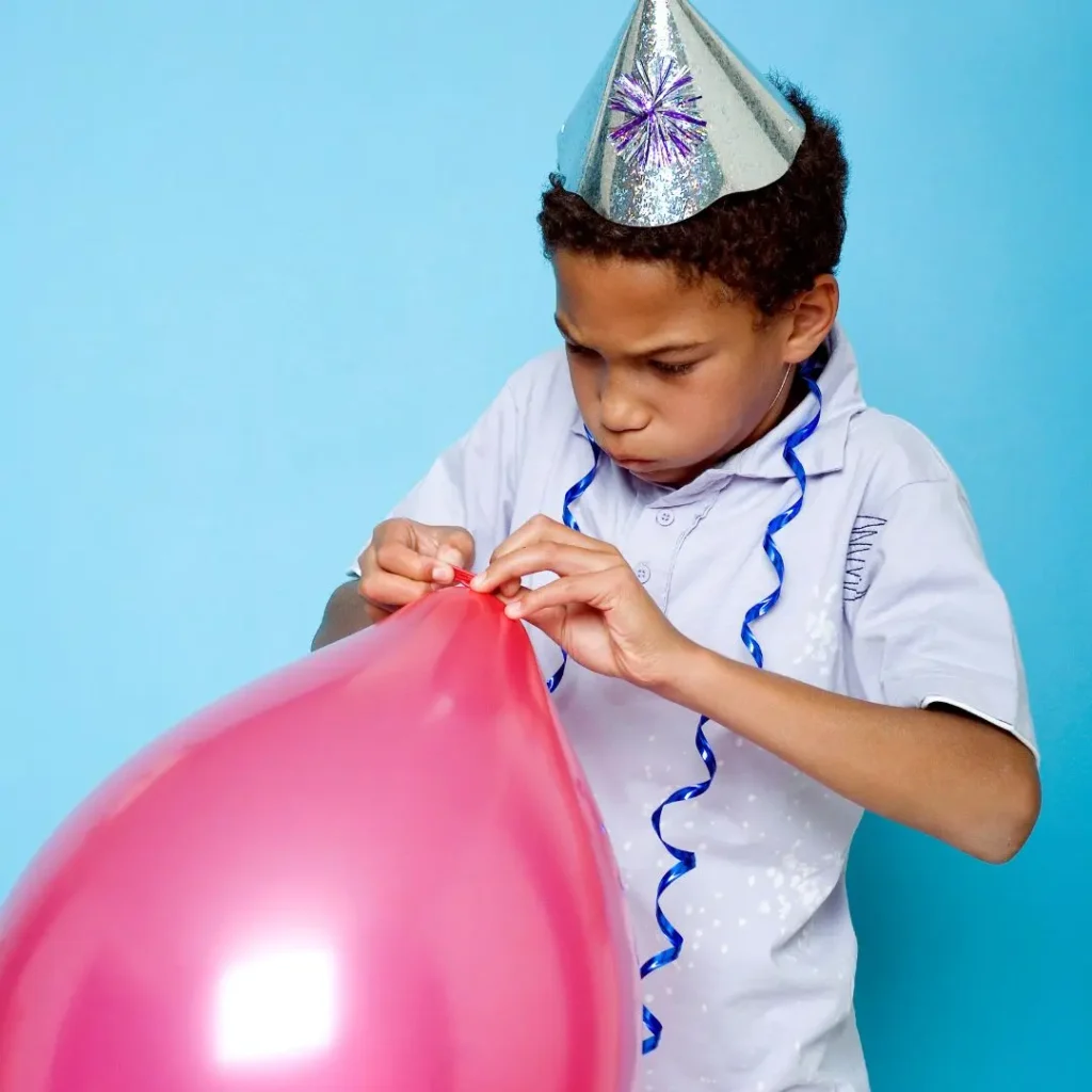 An image of a child tying a balloon